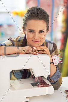 Portrait of happy tailor woman with sewing machine