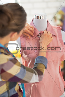 Tailor woman working on clothes in studio. rear view