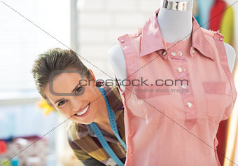 Portrait of smiling tailor woman looking out from mannequin