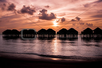 Maldives sunset with water villas silhouette