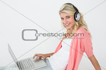 Beautiful woman using laptop while listening to music