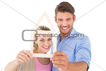 Attractive young couple looking through house outline