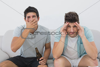 Disappointed soccer fans watching tv