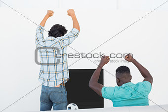 Excited soccer fans cheering while watching tv
