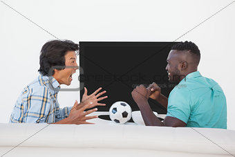 Two excited soccer fans watching tv