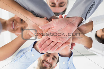 Four workers stacking hands together