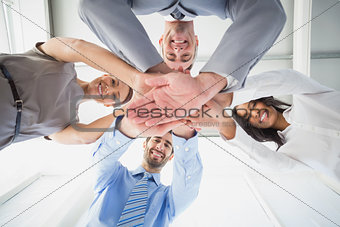 Four workers stacking hands together