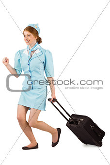 Pretty air hostess pulling suitcase