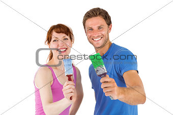 Couple both holding paint brushes