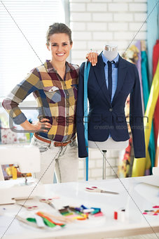 Portrait of tailor woman near mannequin wearing business suit