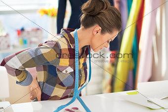 Portrait of tired tailor woman with back pain