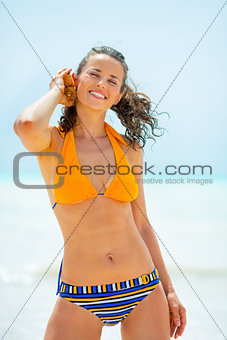 Portrait of relaxed young woman listening sound of sea in shell 