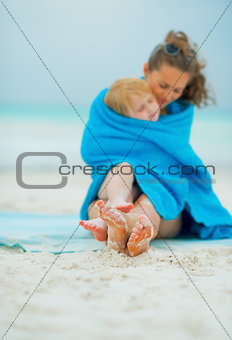 Closeup on mother and baby girl wrapped in towel sitting on beac