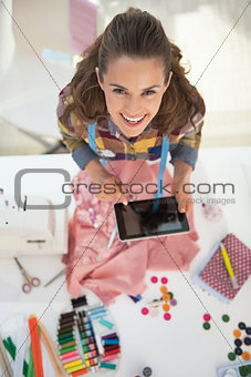 Portrait of happy tailor woman using tablet pc at work