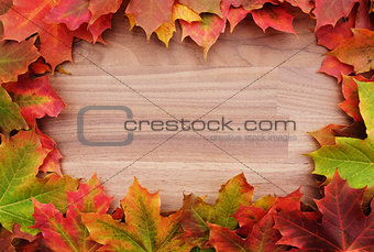 Border of fall maple leaves on wood