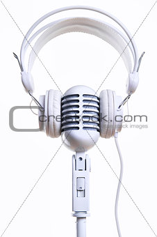 White vintage microphone and headphones over white background
