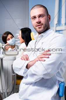 Friendly male dentist with assistant and patient