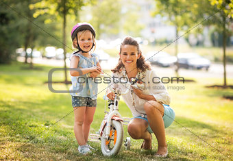 Portrait of happy mother and baby girl with bicycle