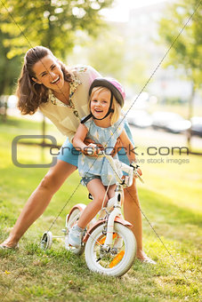 Portrait of mother and baby girl with bicycle