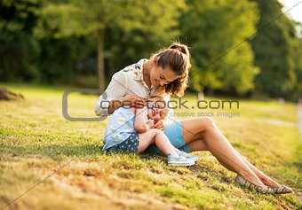 Mother and baby girl sitting outdoors in the evening