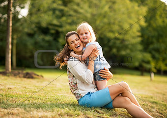 Portrait of happy mother and baby girl hugging in park