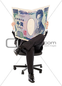 Business man sitting on a chair with japan currency in hands