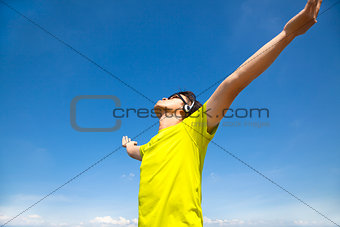 young man enjoying music with blue sky background