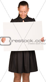 Beautiful girl holding blank white placard and looking at it