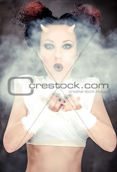 Portrait of devil woman blowing a white powder, conceptual photo