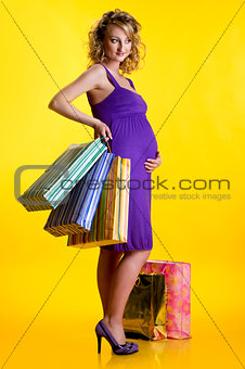 Lovely pregnant woman holding shopping bags