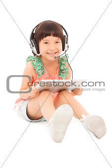 little student girl sitting and holding a tablet with earphone.