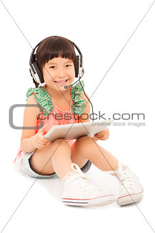 smiling little student girl sitting and holding a tablet