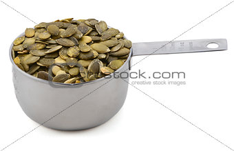 Green pumpkin seeds in a cup measure