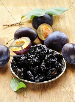 Dried plums prunes and fresh berries on the wooden table