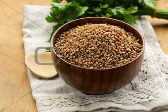 raw buckwheat groats in a wooden bowl on  table