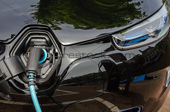 Charging modern electric car with power supply plugged in