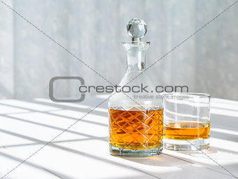 Whisky decanter and rocks glass by the window
