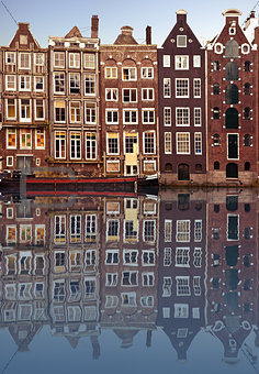 Typical Amsterdam houses reflected in the canal with blue sky background