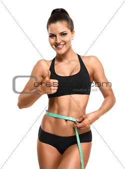 Athletic woman measuring her waist  and showing thumb up isolate