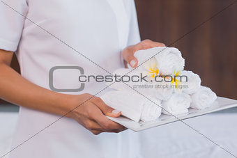 Mid section of masseur holding rolled up towels