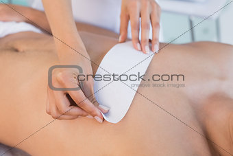 Beauty therapist waxing mans chest