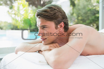 Handsome man lying on massage table at spa center
