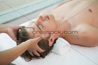 Handsome man receiving head massage at spa center