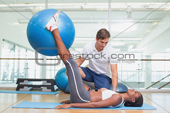 Personal trainer working with client holding exercise ball
