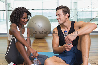 Personal trainer and client smiling at each other on exercise mat
