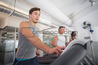 Fit man running on treadmill listening to music