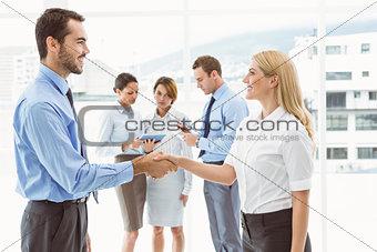 Executives shaking hands with colleagues behind
