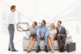 Businessman shaking hands with woman besides people waiting for interview