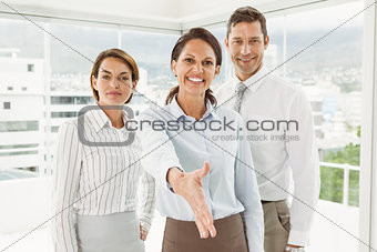 Businesswoman with colleagues offering handshake at office
