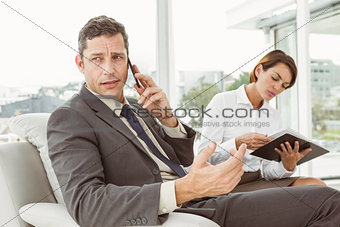 Businessman on call while secretary looks at diary